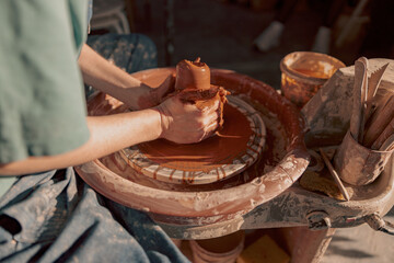 Clay artist modeling product on potter wheel in workshop