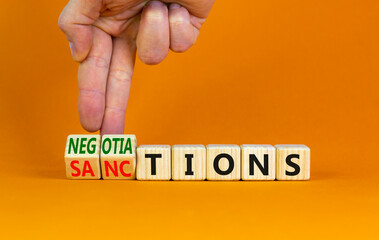 Sanctions or negotiations symbol. Businessman turns cubes, changes the word sanctions to...