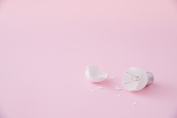 Egg lightbulb on pastel pink background with broken or shattered egg shell. Minimal concept. Easter inspiration. Flat lay. Broken idea. Lightbulb idea concept.