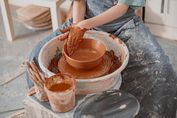 Young woman works on pottery wheel in atelier