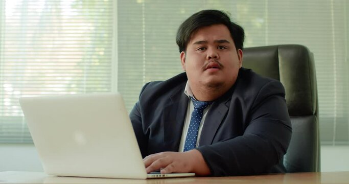 Asian business man which has a fat figure and funny personality, wearing a suit like an executive using a laptop in the officeLater, a voice spoke to him, causing him to turn around and listen.