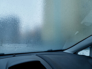 Obraz premium Frozen, icy car windshield. Use of the car in winter and during adverse weather conditions. Shooting from a car.