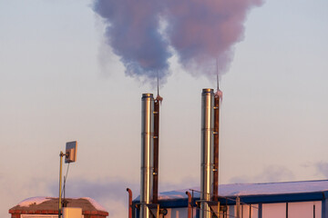 Smoke from the boiler room chimney, roofs of buildings in the snow.