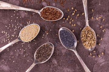 Assorted
 of useful seeds in spoons on a gray background.Lei flat.