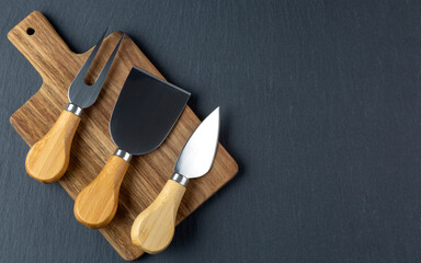 Cheese cutter set with wooden handles. Group of cheese knives on the cutting board.Top view