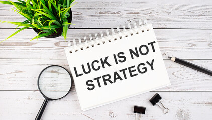 LUCK IS NOT STRATEGY text concept write on notebook with office tools on the wooden background