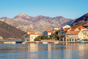Fototapeta na wymiar Calm sunny winter day. Beautiful Mediterranean landscape. Montenegro, Adriatic Sea, coast of Kotor Bay. Small seaside Lepetane village at foot of mountains