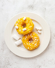 Two donuts with marshmallows served on a plate
