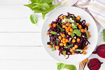 Healthy low carb beet noodles with spinach and chickpeas. Above view table scene on a white wood...