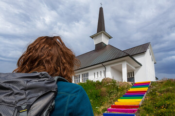 Woman walking on rainbow staircase leading to Hólmavík Church (Hólmavíkurkirkja) supporting equal rights for LGBT people community. Holmavik, Iceland