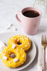 Two donuts with marshmallows and a cup of tea or coffee
