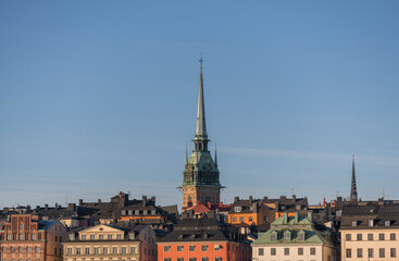 Fototapeta na wymiar Panorama view of roofs of the old town Gamla Stan with spire of the German church and the Riddarholmskyrkan a sunny and snowy winter day in Stockholm