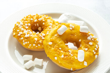 Two donuts with marshmallows on a white plate