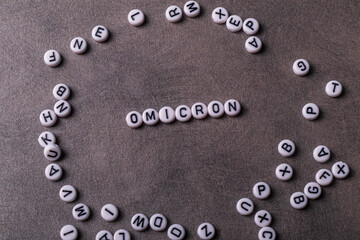 the words covid, omicron, are written in letters on a gray background. there are a lot of toy inscriptions nearby.