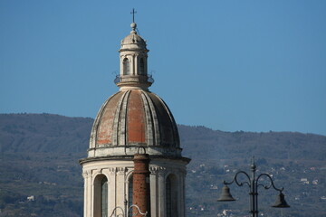 Primo piano del campanile della chiesa di riposto, in Sicilia, che si staglia alto con dietro le...