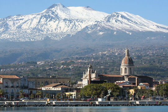 Foto panoramica del paese portuale di Riposto, con il mare in primo piano, il campanile e il vulcano etna sullo sfondo