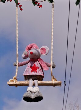 Rosa Stoffmaus auf einer Schaukel vor Himmel