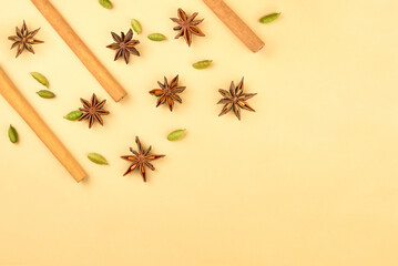 Cinnamon sticks, cardamom and star anise on a beige background, top view.