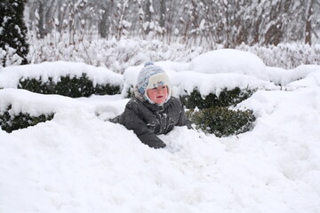 Fototapeta na wymiar Little boy playing in a snowy park