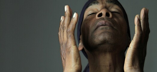 man praying to god with hands together on grey background stock photo