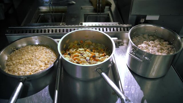 cooking. pots of food. close-up. there are pans of freshly cooked food on the stove. buffet restaurant kitchen