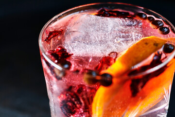 Gin Tonic cocktail with hibiscus, orange slice and pepper