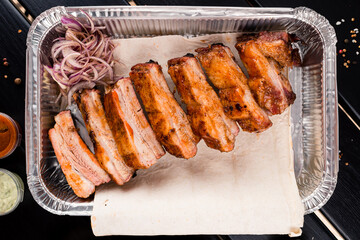 BBQ grilled ribs in a metal tray for delivery. Take out concept. In foil delivery box, food take away