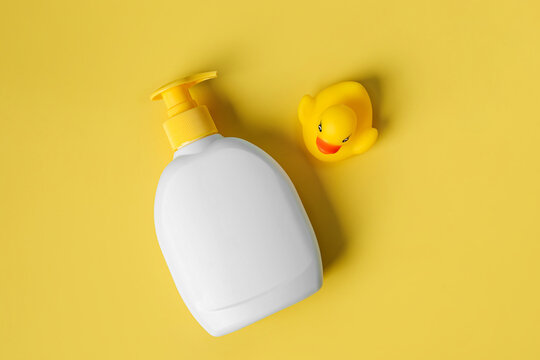 Soap or shampoo bottle with cute duck on yellow background. Baby bathing accessories