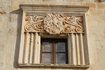 A window with a coat of arms and inscriptions carved in stone in a house in the town of Perazancas de Ojeda