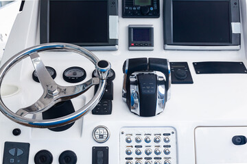 Luxury yacht control panel with steering wheel, gear levers, navigation devices, control buttons and on-board computer.
