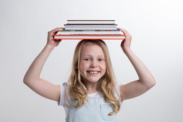 A beautiful girl is holding a lot of books in her hands.