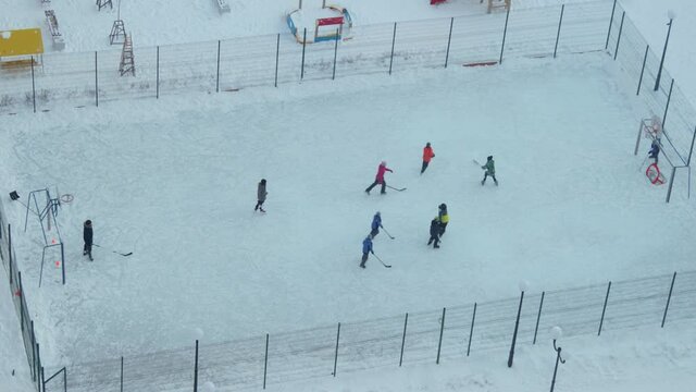 Children playing hockey on a yard rink