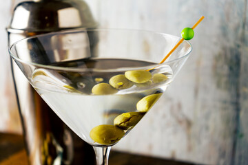 Close-up of a martini glass with olives on a light background.