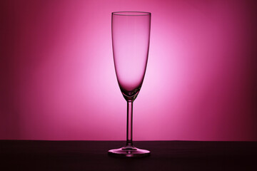One champagne glass on pink background. Luxury drink glass in purple lights. Copy space, isolate, selective focus