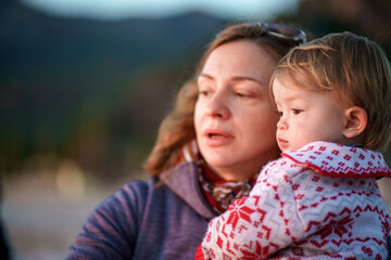 Mom and daughter in warm sweaters are on the shore of the winter sea. The family spends time in nature. Relaxation. Vacation