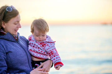 Vacation. The family spends time in nature. Relaxation. Mom and daughter in warm sweaters are on the shore of the winter sea