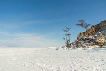 Sacred Cape Burkhan on Olkhon Island in winter. View from the ice of frozen Lake Baikal on a sunny day - 480615955