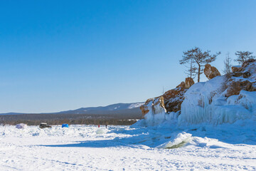 Tent tourist camp on the ice of a frozen lake. Active winter tourism, ice fishing. Russia, Lake Baikal, Olkhon Island. Snow season. - 480615960