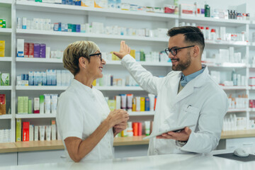 Happy young male pharmacist working with senior colleague