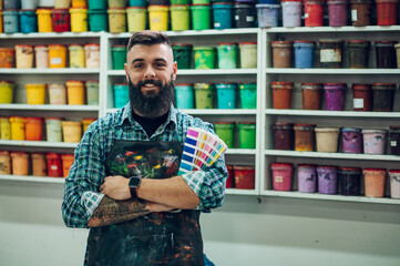 Male worker posing while mixing colors for screen printing in a workshop