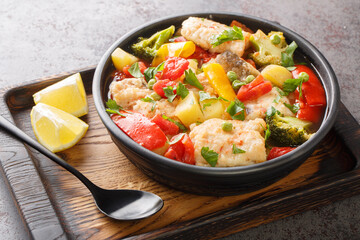 Delicious fish ragout with fresh summer vegetables close-up in a bowl on the table. horizontal