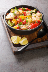 Thick fish soup with peppers, potatoes, peas, onions, broccoli and tomatoes close-up in a bowl on the table. vertical