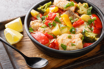 Dietary fish stew with peppers, potatoes, peas, onions, broccoli and tomatoes close-up in a bowl on the table. horizontal
