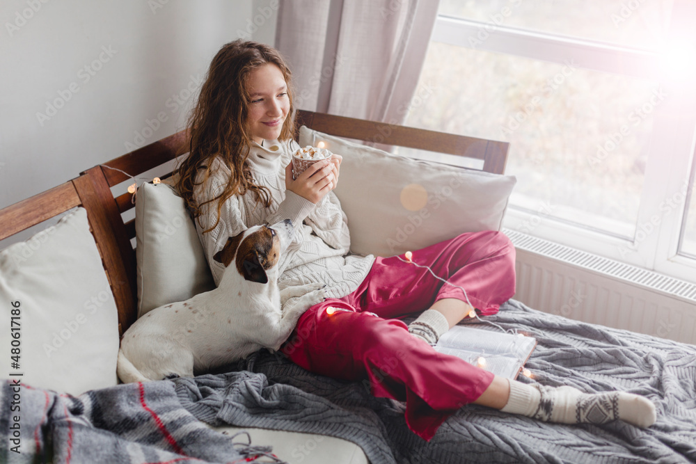 Wall mural Young woman with dog drinking warm coffee at home