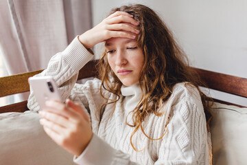  Upset girl Sitting on couch at home with cellphone