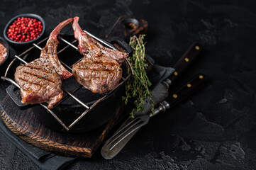 Grilled lamb mutton meat chops steaks on a grill. Black background. Top view. Copy space