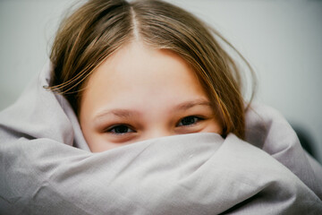 cheerful teen girl wrapped in a blanket