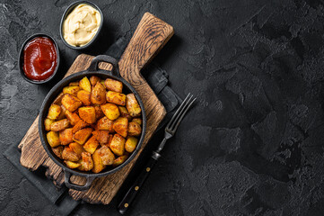 Patatas bravas, spicy potatoes, a Spanish dish with fried potato and a spicy garlic sauce. Black...