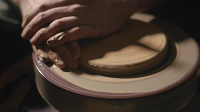Artisan hands forming a plate from clay on a potter's wheel in slow motion