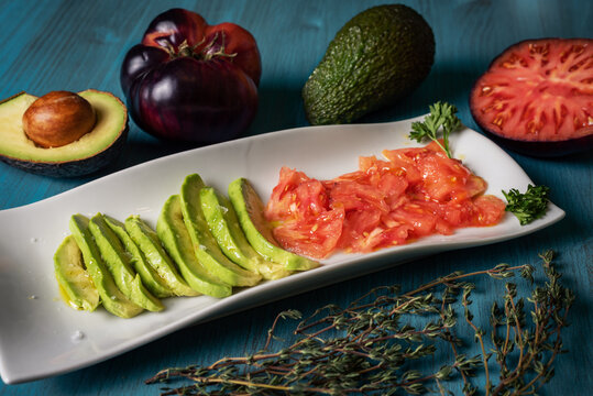 Plate to snack with avocado and tomato accompanied by oil and salt flakes.